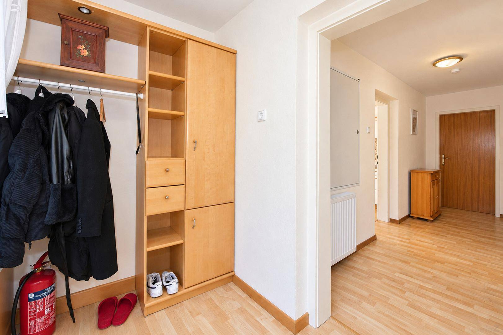 Geräumiger Flur mit hellem Laminatboden und praktischem Holzschrank für Kleidung.
