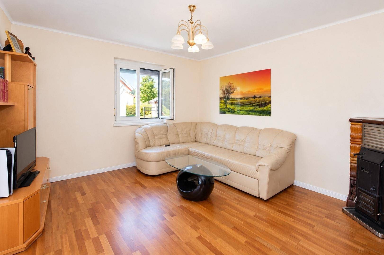 Gemütliches Wohnzimmer mit Ecksofa, Holzboden und Kaminofen für entspannte Abende.