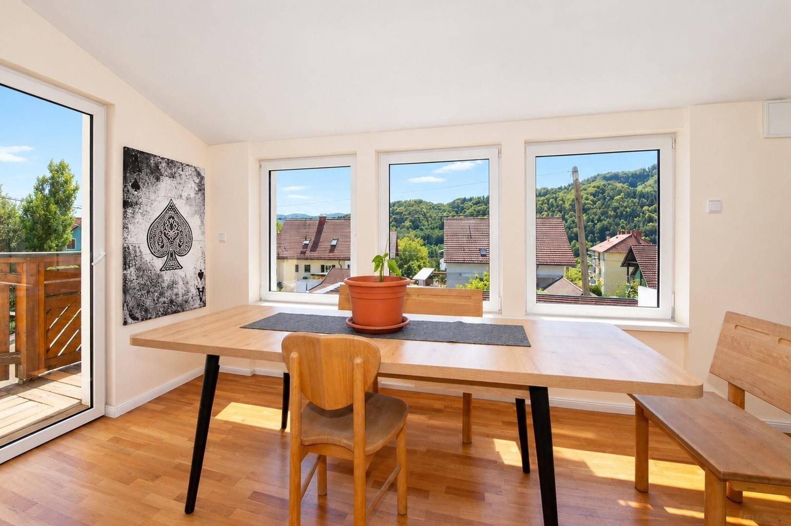 Heller Essbereich mit Holztisch, großen Fenstern und weitem Blick in die Natur.