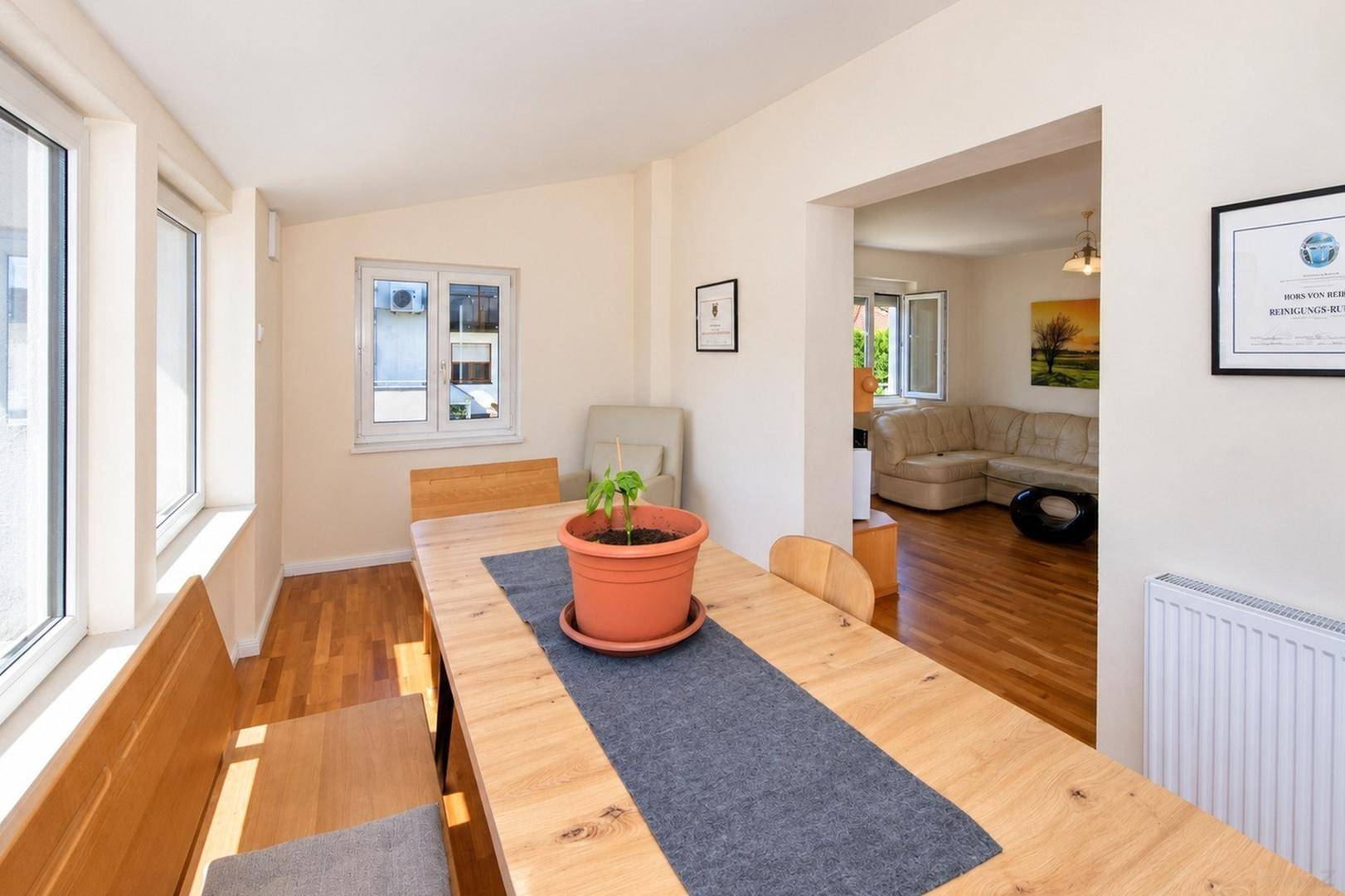 Essbereich mit Blick in das angrenzende Wohnzimmer, hell und mit Holzboden.