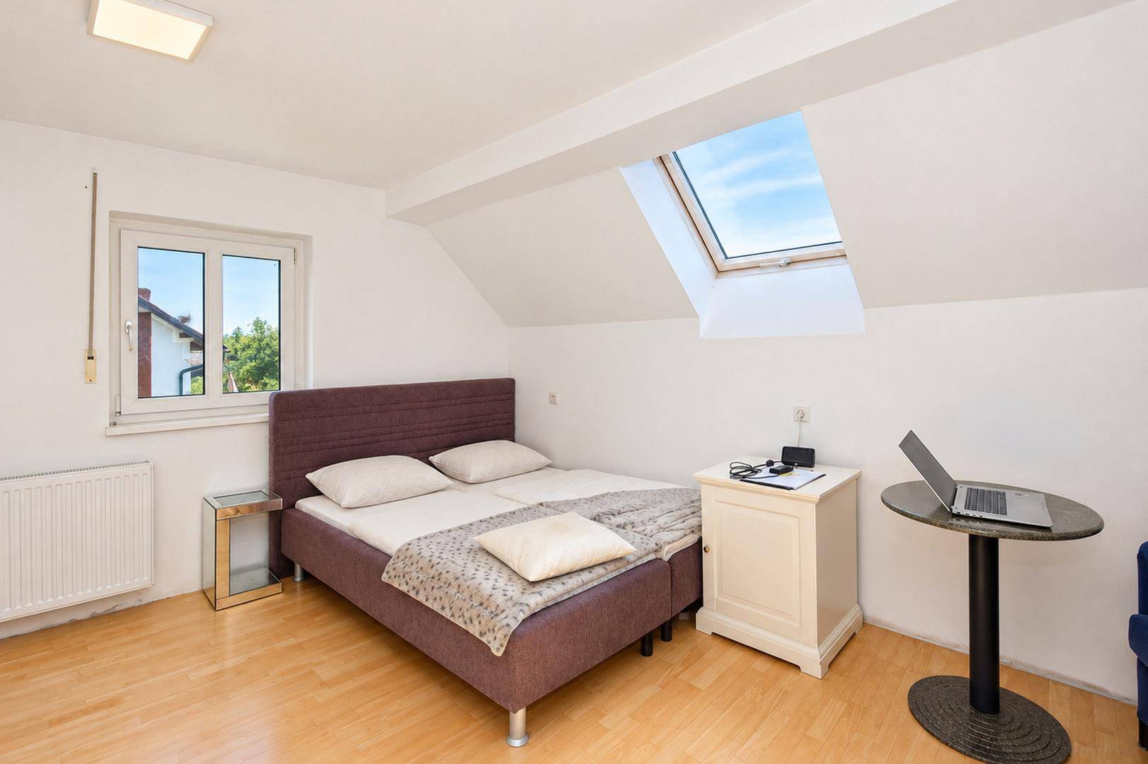 Gemütliches Schlafzimmer mit Doppelbett, Holzboden und Dachfenster für viel Tageslicht.