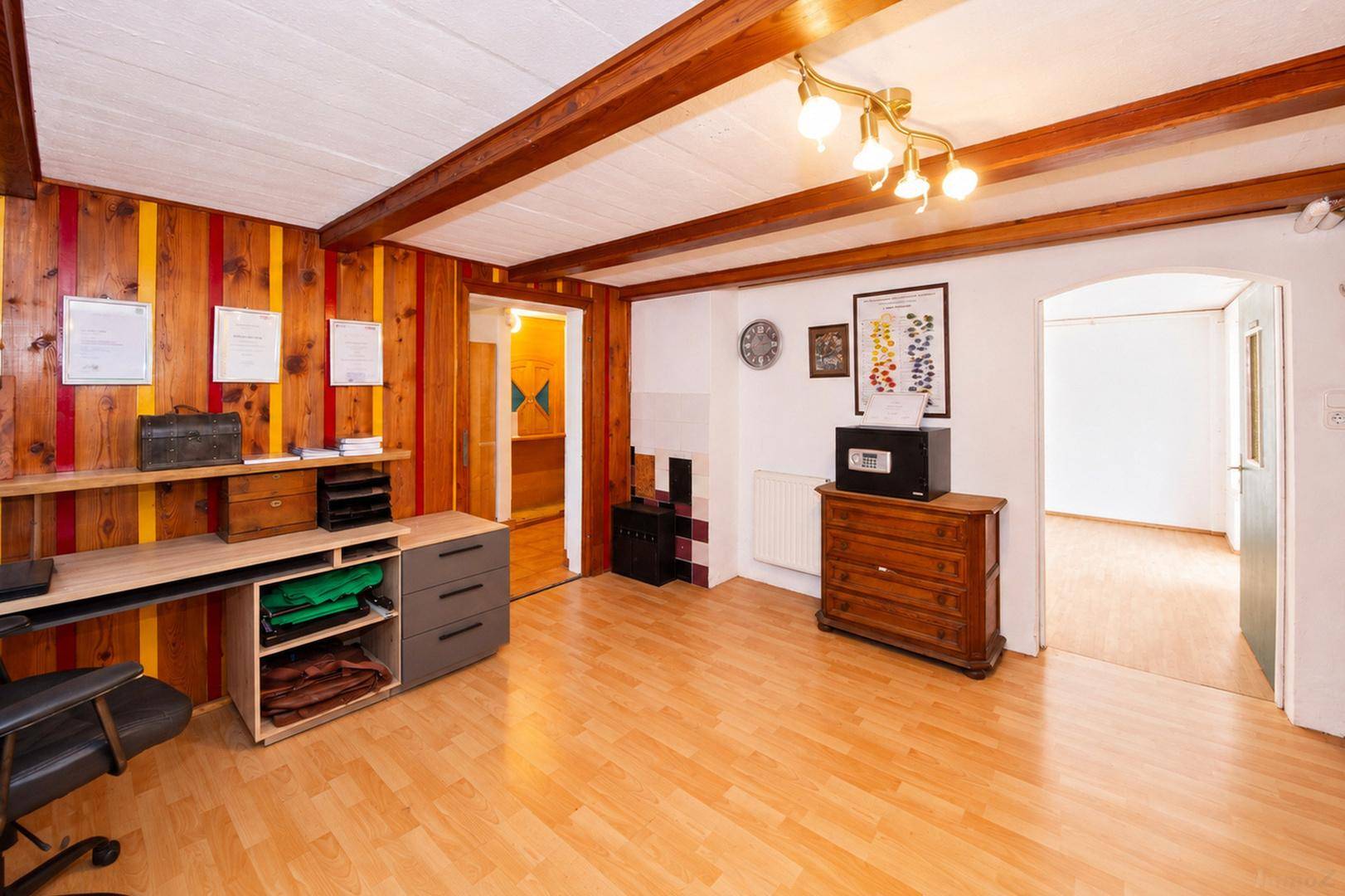 Arbeitszimmer mit Holzboden, Holzvertäfelung, Deckenbalken und Schreibtischbereich.