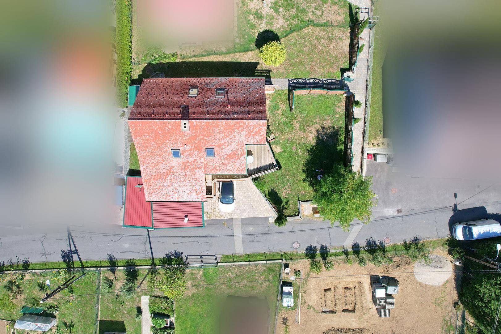 Luftaufnahme des Hauses mit rotem Dach, Garten und angrenzender Straße.