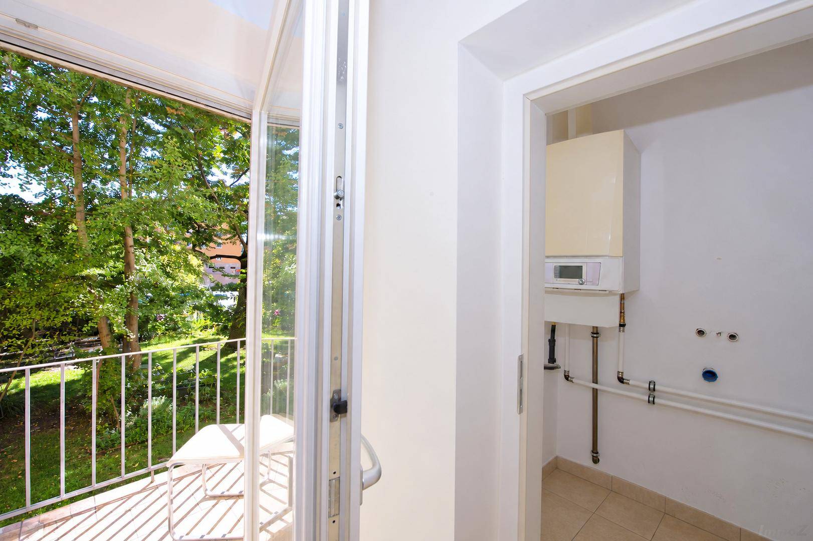 Hauswirtschaftsraum mit Heizungsanlage und Anschlüssen für Waschmaschine, neben Balkon.