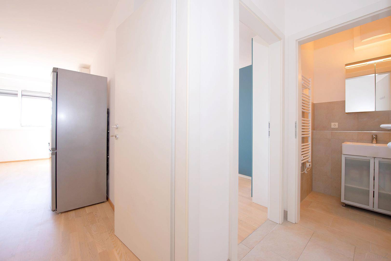 Heller Flur mit Zugang zu Schlafzimmer und Badezimmer, ausgestattet mit Fliesenboden.
