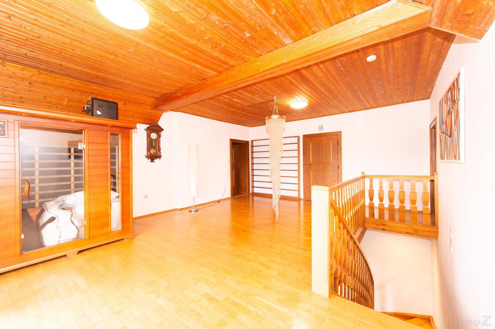 Geräumiger Flur mit Holzdecke, Parkettboden, Sauna und Treppenaufgang.