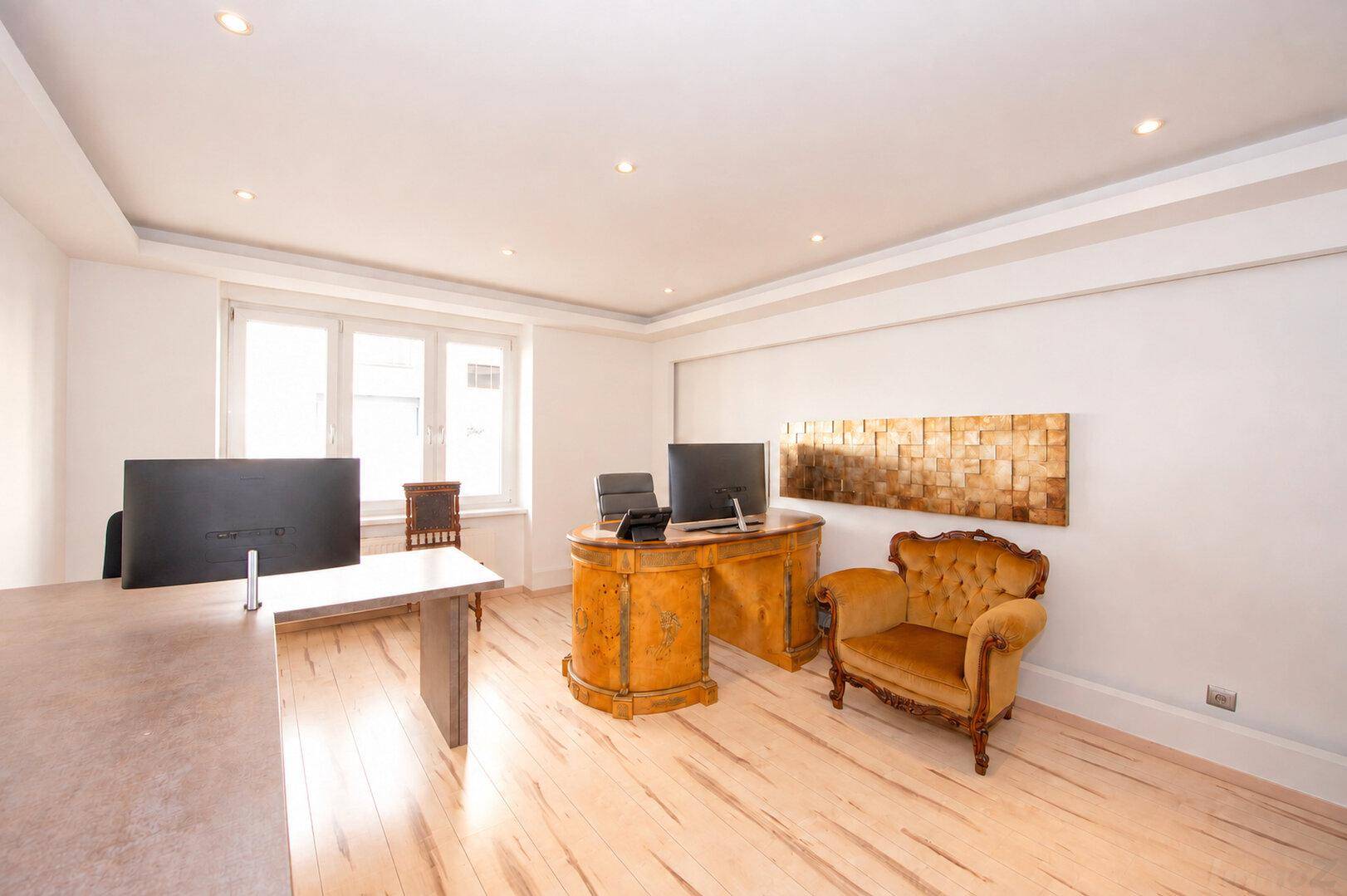 Elegantes Büro mit klassischem Schreibtisch, Sessel und moderner Kunst an der Wand.
