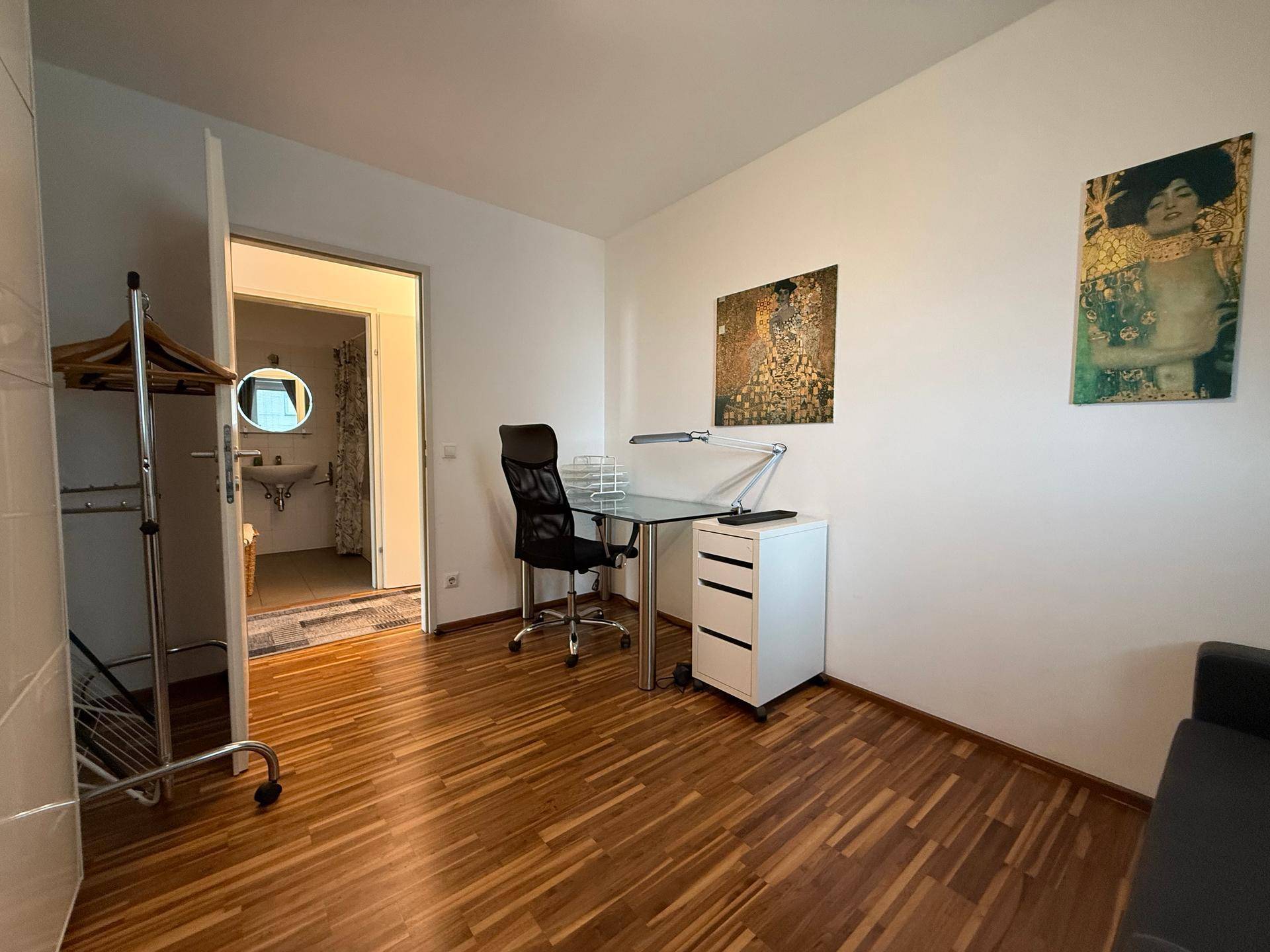 Funktionales Arbeitszimmer mit Schreibtisch, Bürostuhl und direktem Zugang zu einem Badezimmer.