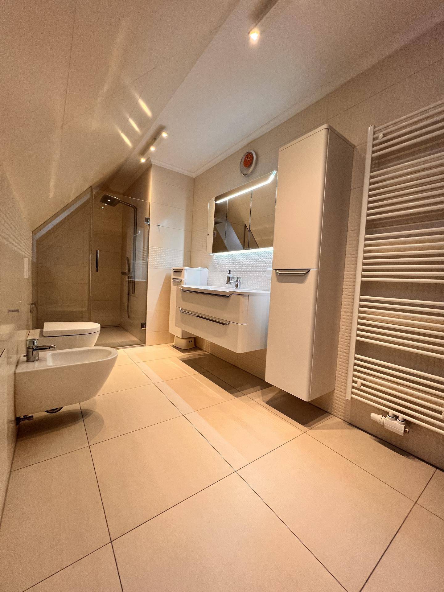 Modernes Badezimmer mit begehbarer Dusche, Bidet, beheiztem Handtuchhalter und Dachschräge.