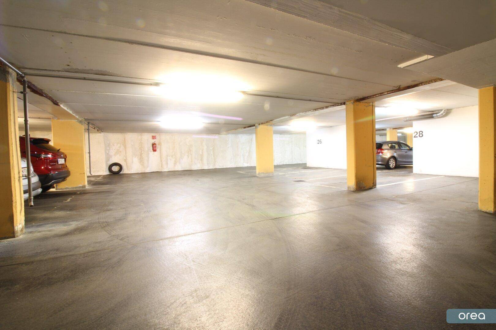Helle Tiefgarage mit ausreichend Platz und nummerierten Stellplätzen für Fahrzeuge.