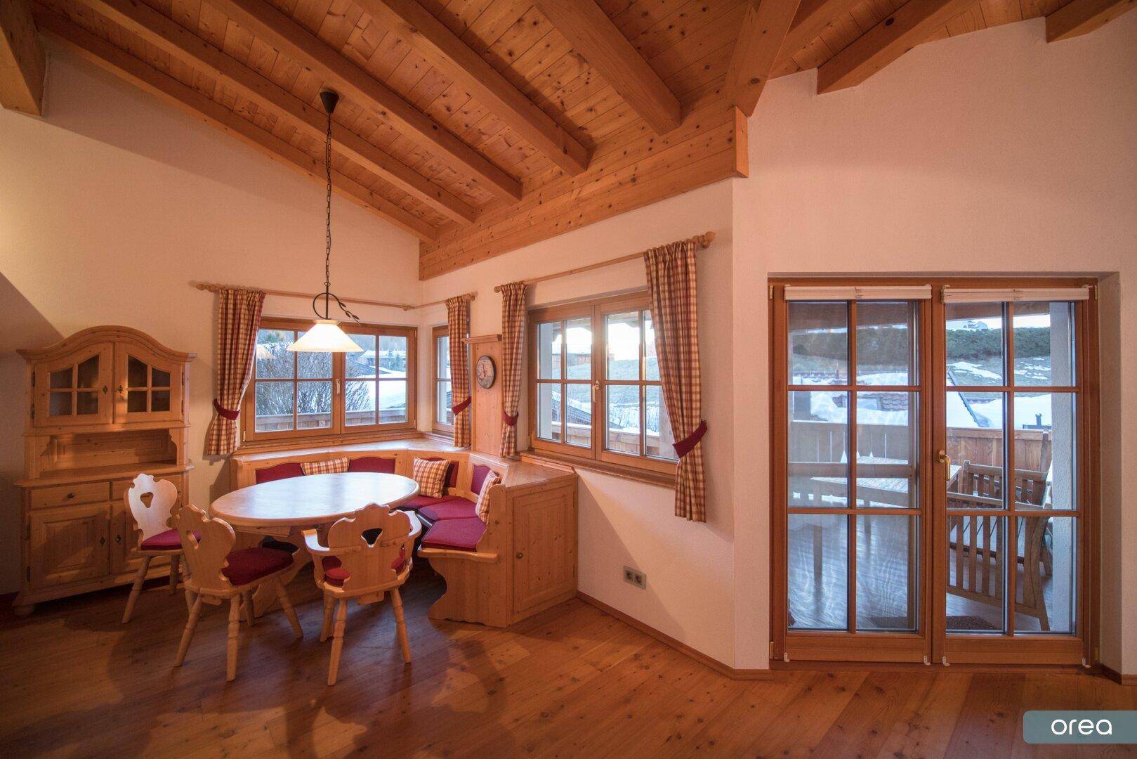 Traditioneller Essbereich mit Eckbank, Holztisch und Zugang zu einem Balkon im Chalet.