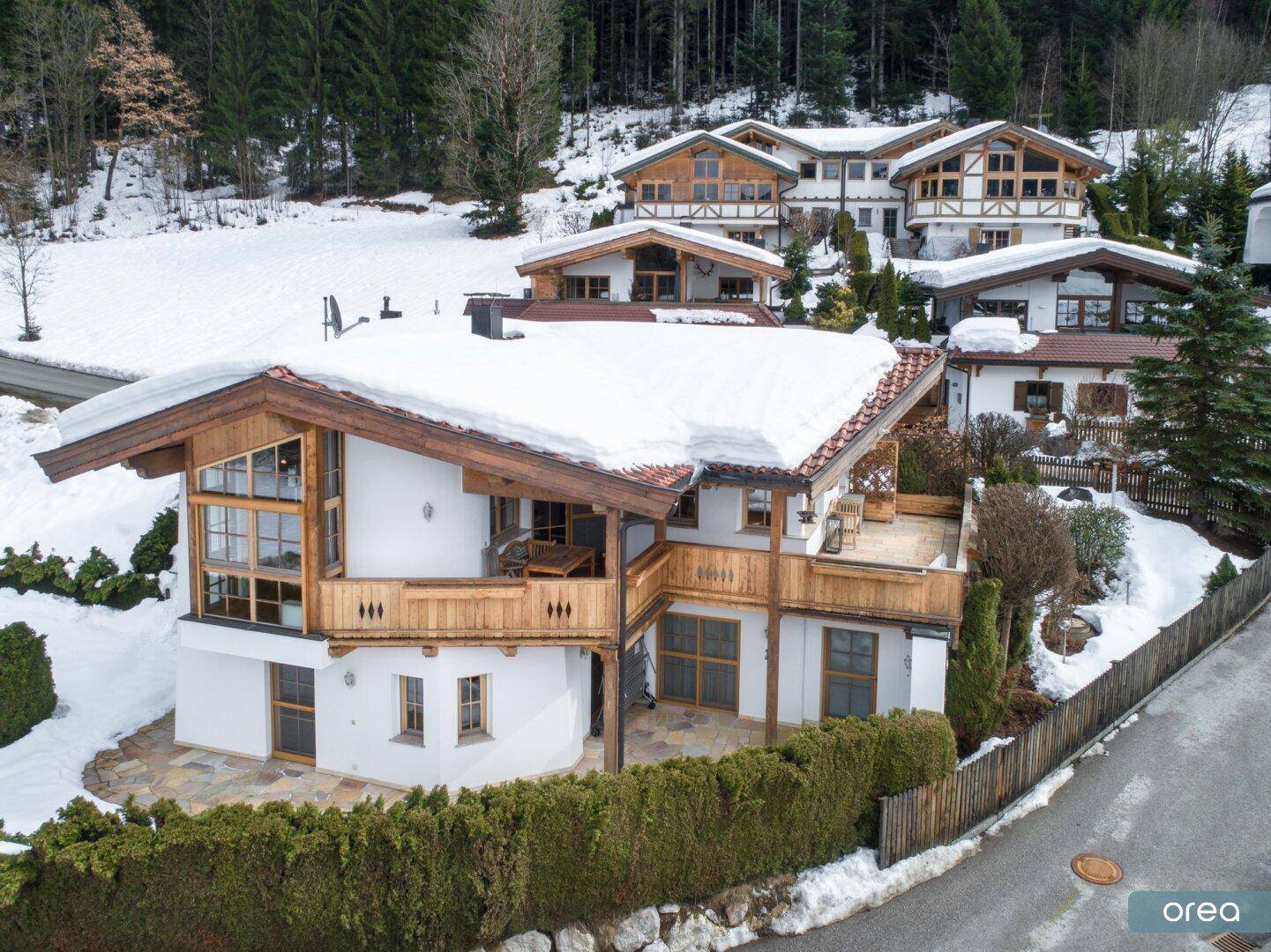 Idyllisches Chalet in winterlicher Berglandschaft mit Holzbalkonen und gepflegter Außenanlage.