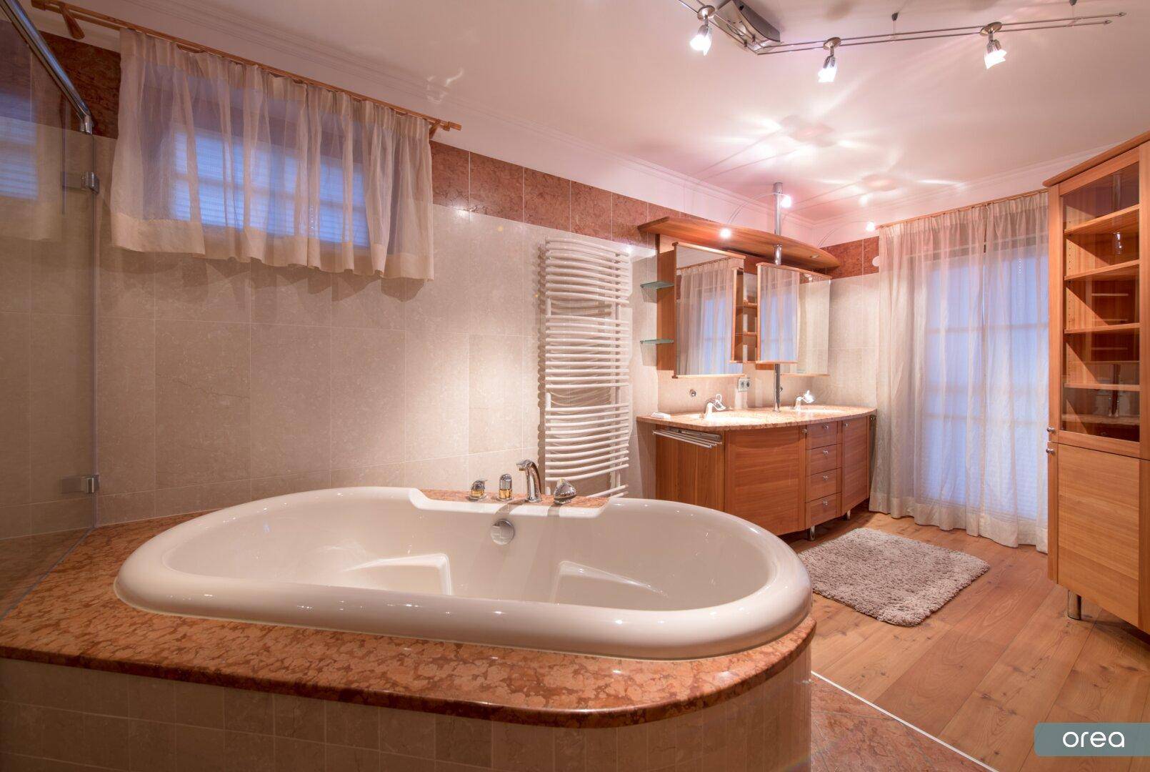 Geräumiges Badezimmer mit Badewanne, Doppelwaschbecken und beheiztem Handtuchhalter.