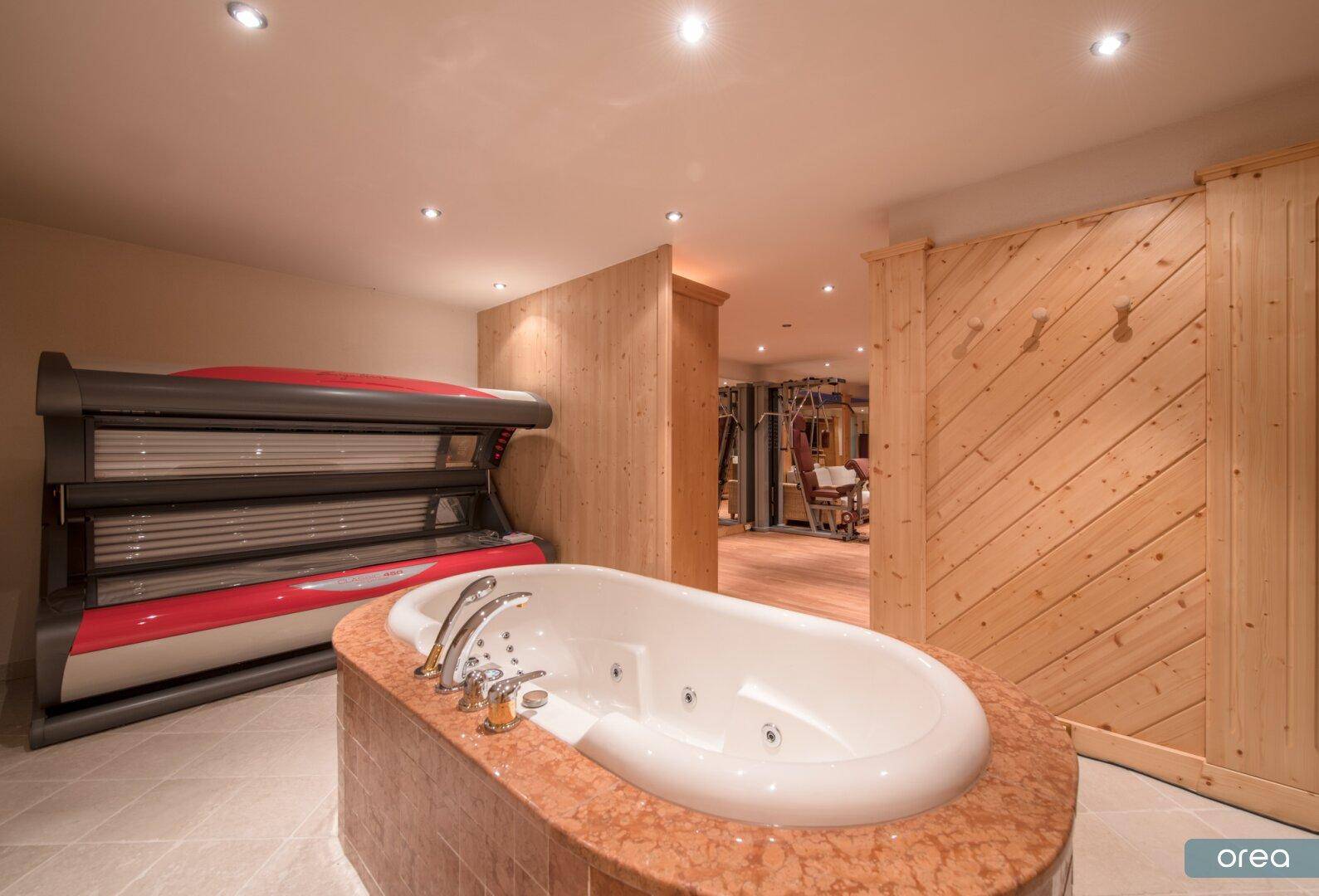 Luxuriöser Wellnessbereich mit Whirlpool, Solarium und Zugang zum Fitnessraum.