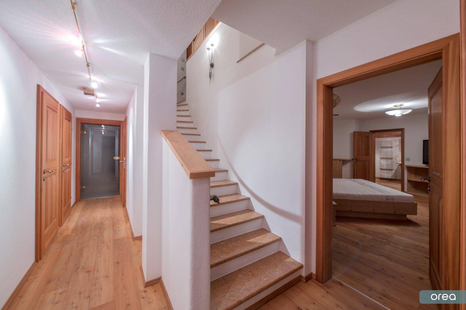 Heller Flur mit Holztreppe und Holzböden, der zu den oberen Etagen führt.