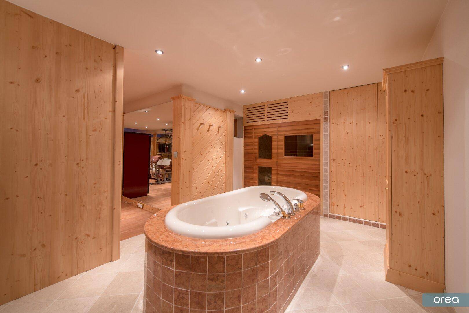 Exklusiver Wellnessbereich mit Whirlpool, Sauna und Holzelementen für Entspannung.