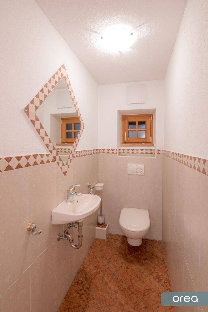 Kleines Gäste-WC mit Waschtisch, Toilette und Fenster im traditionellen Stil.
