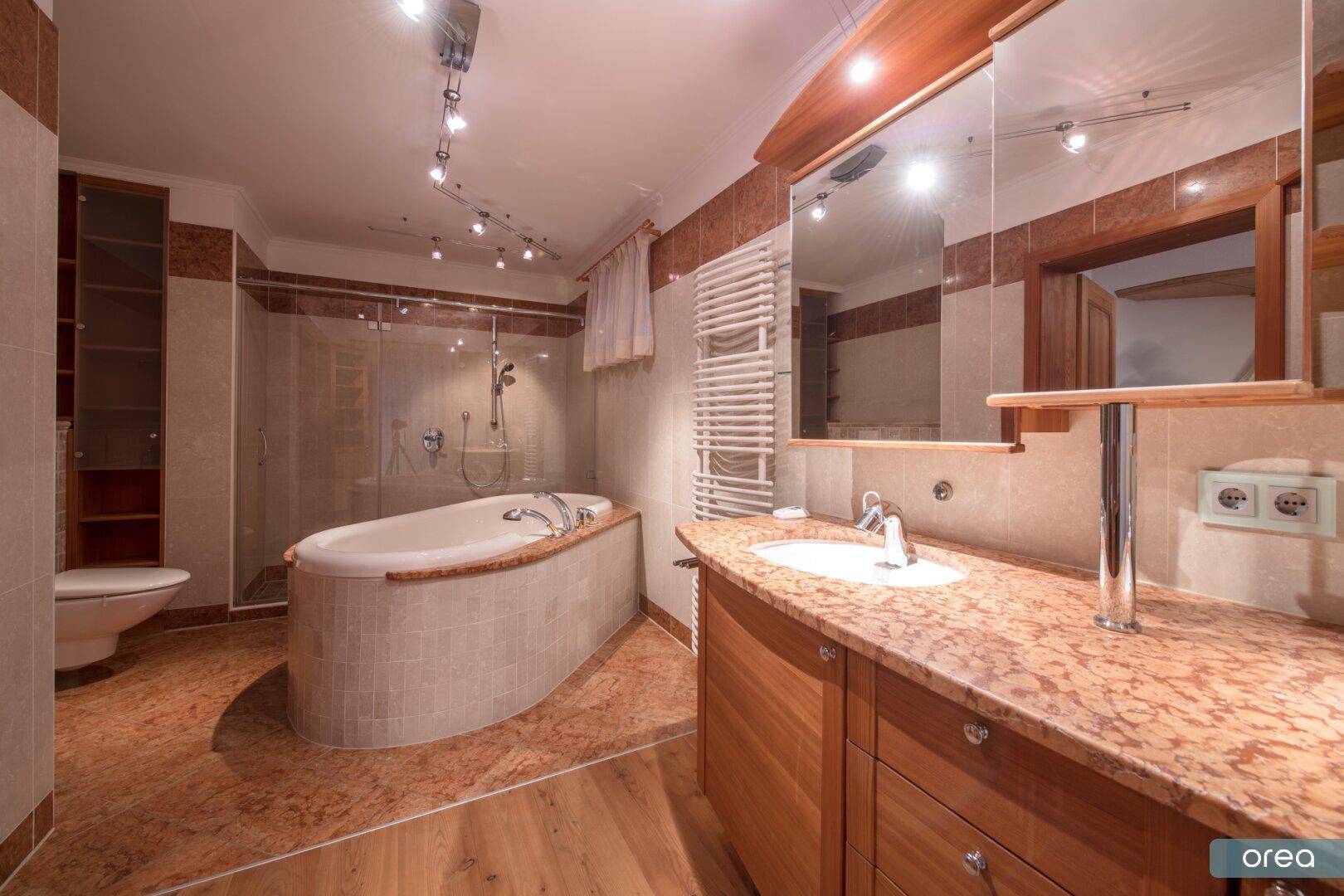 Elegantes Badezimmer mit Badewanne, Dusche und Waschtisch mit Granitplatte.