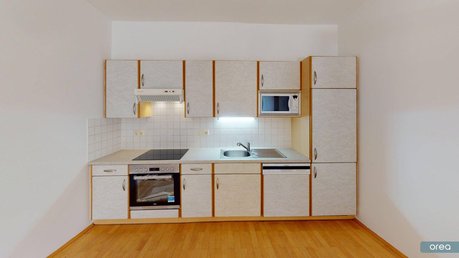Funktionale Einbauküche mit hellen Schränken, Kochfeld, Backofen und Spülmaschine.