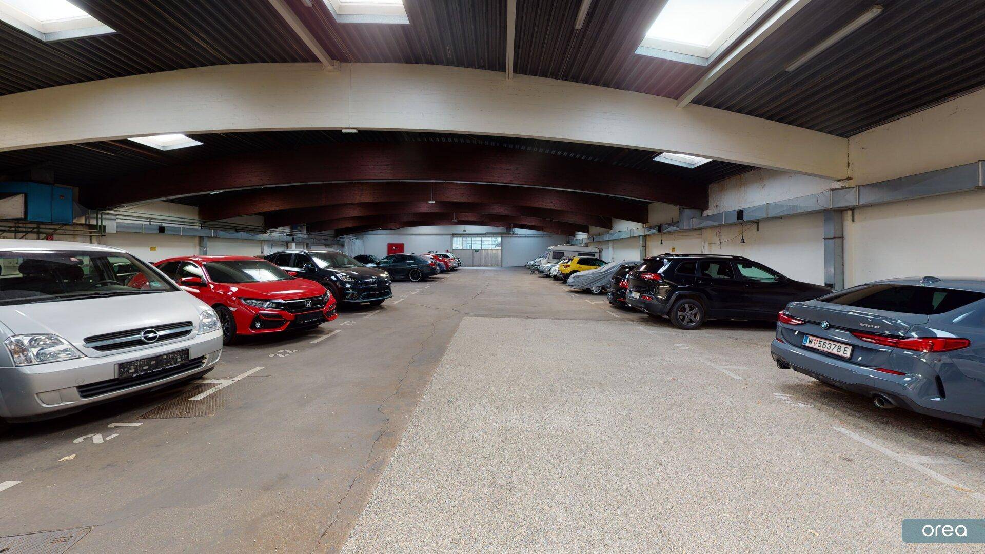Geräumige Tiefgarage mit zahlreichen Stellplätzen und Oberlichtern für natürliches Tageslicht.