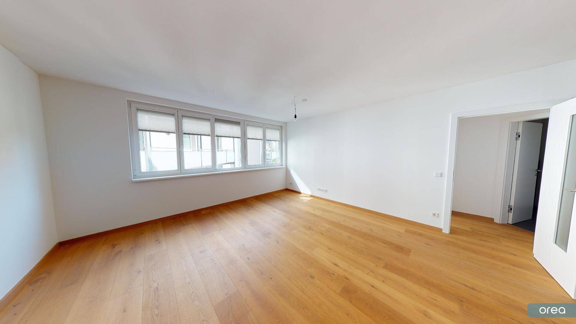 Geräumiger Wohnbereich mit hellem Parkettboden und Zugang zu weiteren Räumen.