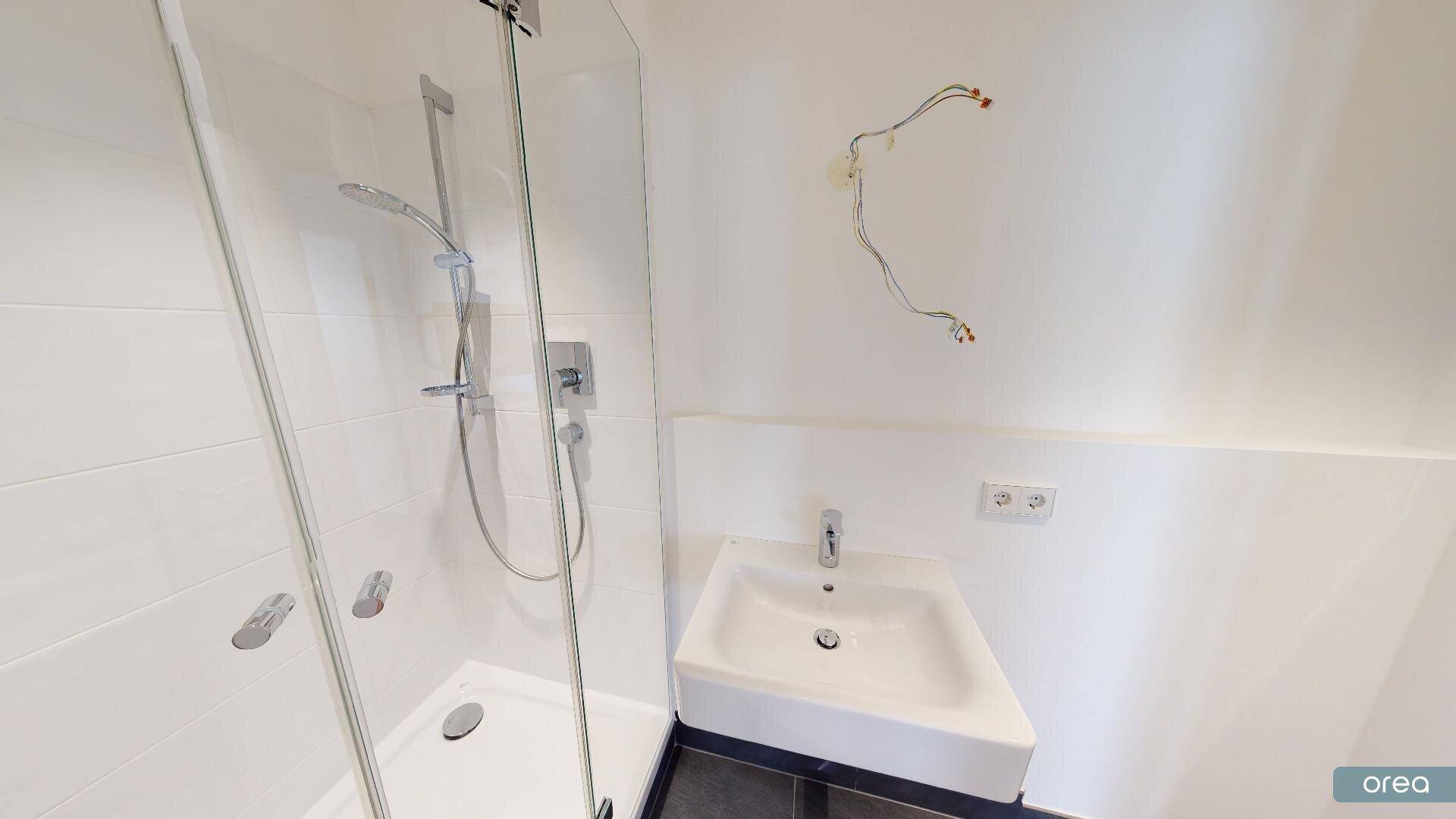 Modernes Badezimmer mit ebenerdiger Dusche und einem einzelnen Waschbecken.