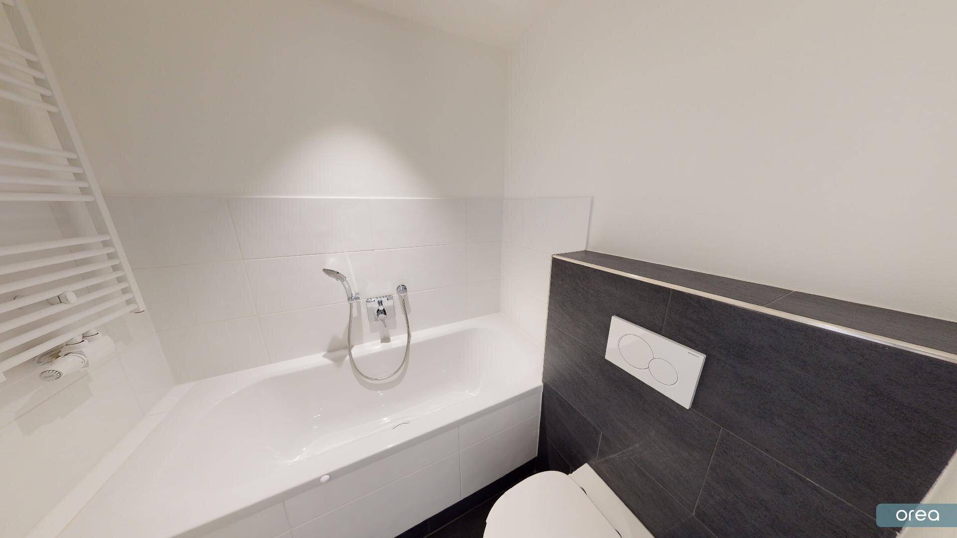 Badezimmer mit Badewanne, wandhängendem WC und beheiztem Handtuchhalter.