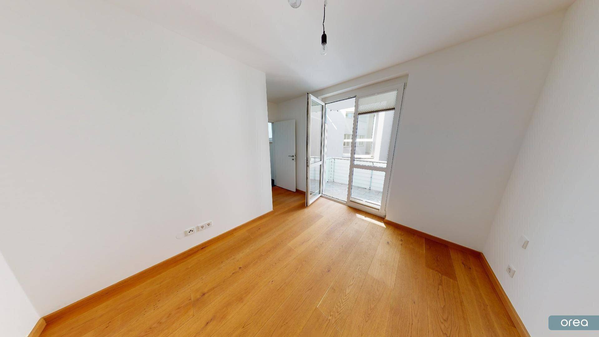 Geräumiges Zimmer mit Parkettboden und direktem Zugang zu einem Balkon.