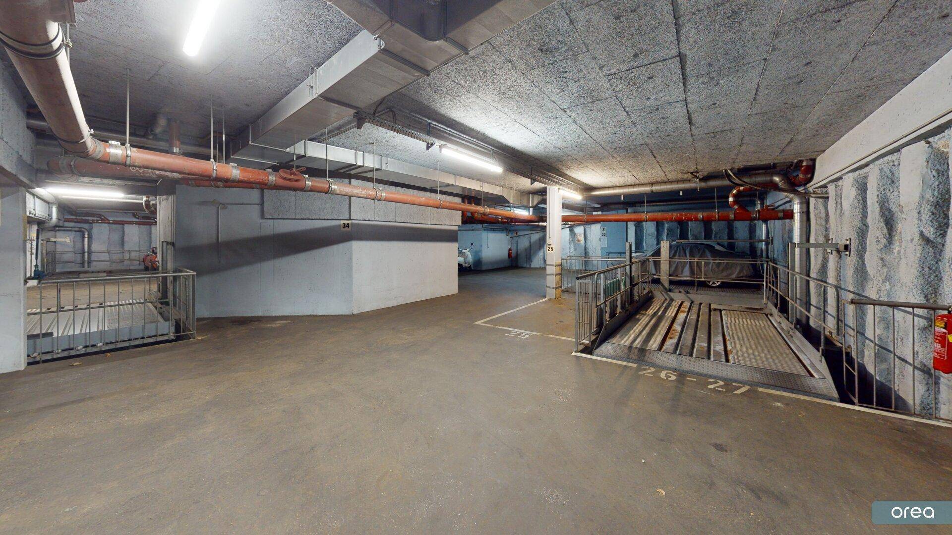Weitläufige Tiefgarage mit Betonkonstruktion und mechanischem Parksystem für Fahrzeuge.