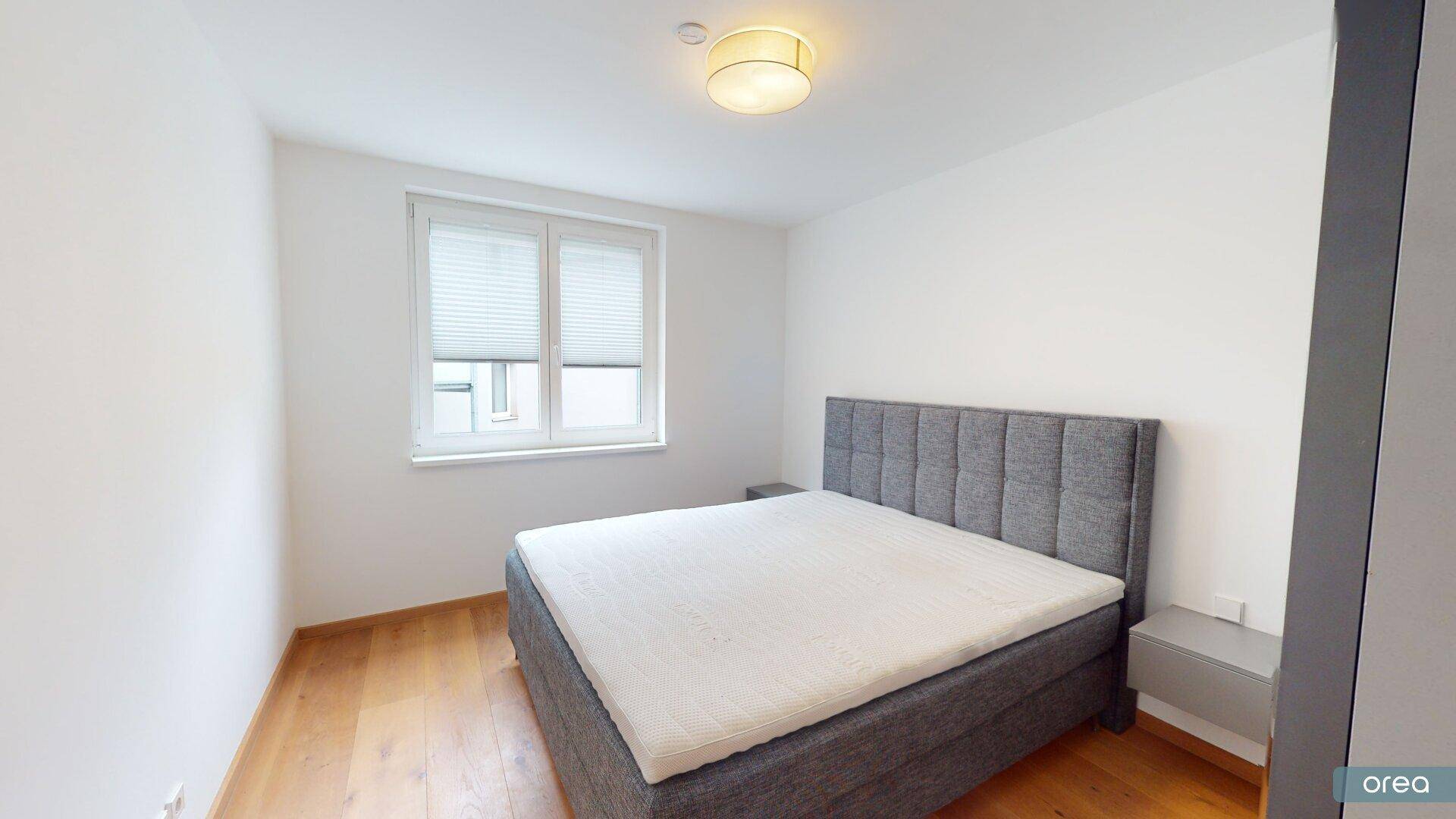 Helles Schlafzimmer mit großem Doppelbett und Fenster für natürliches Licht.