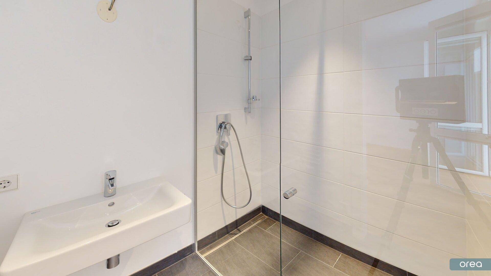 Modernes Badezimmer mit begehbarer Dusche und wandmontiertem Waschbecken.