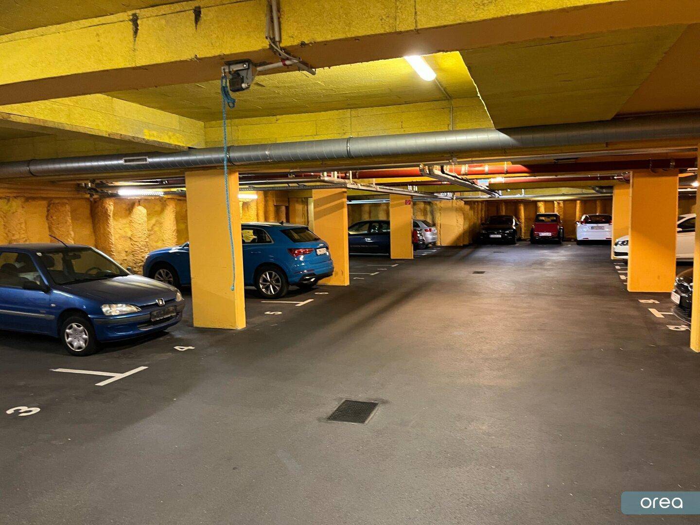 Geräumige Tiefgarage mit zahlreichen Parkplätzen und der typischen gelben Farbgebung der Wände.