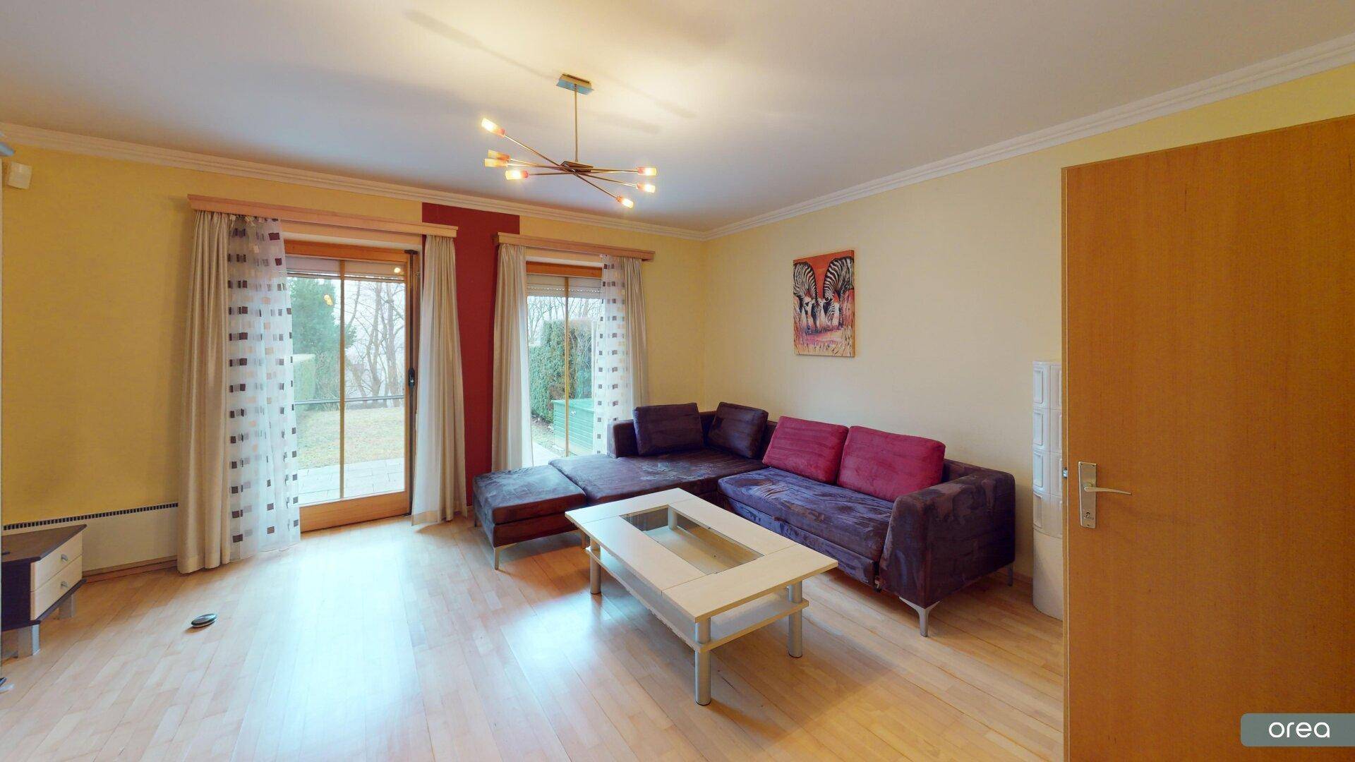 Helles Wohnzimmer mit Parkettboden, gemütlichem Sofa und Zugang zum Garten.