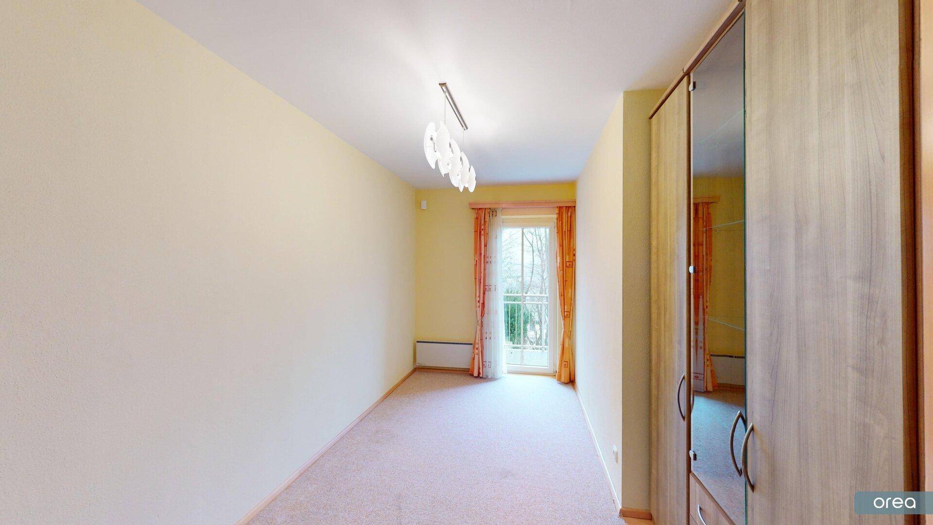 Schlafzimmer mit Teppichboden, Kleiderschrank und Zugang zu einem französischen Balkon.
