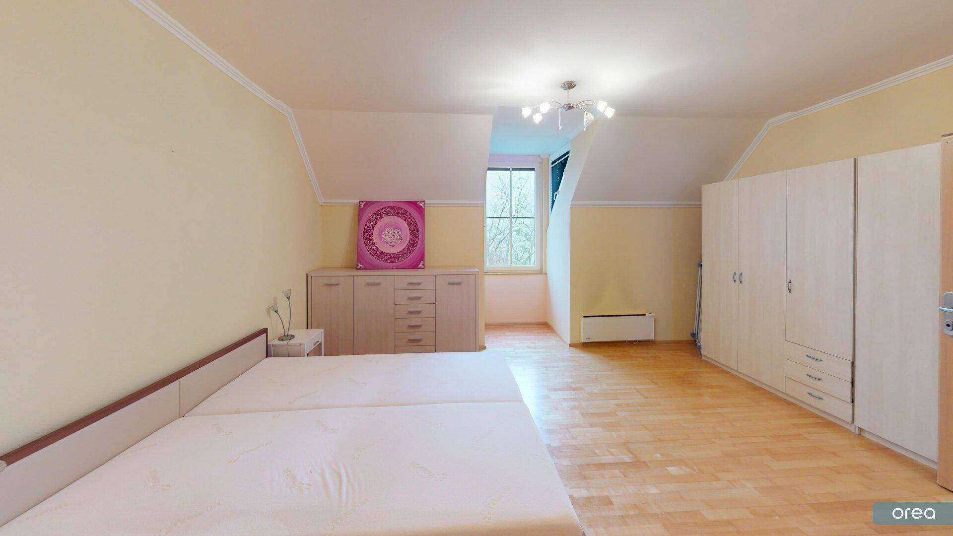 Geräumiges Schlafzimmer im Dachgeschoss mit Doppelbett, Schränken und Dachschräge.