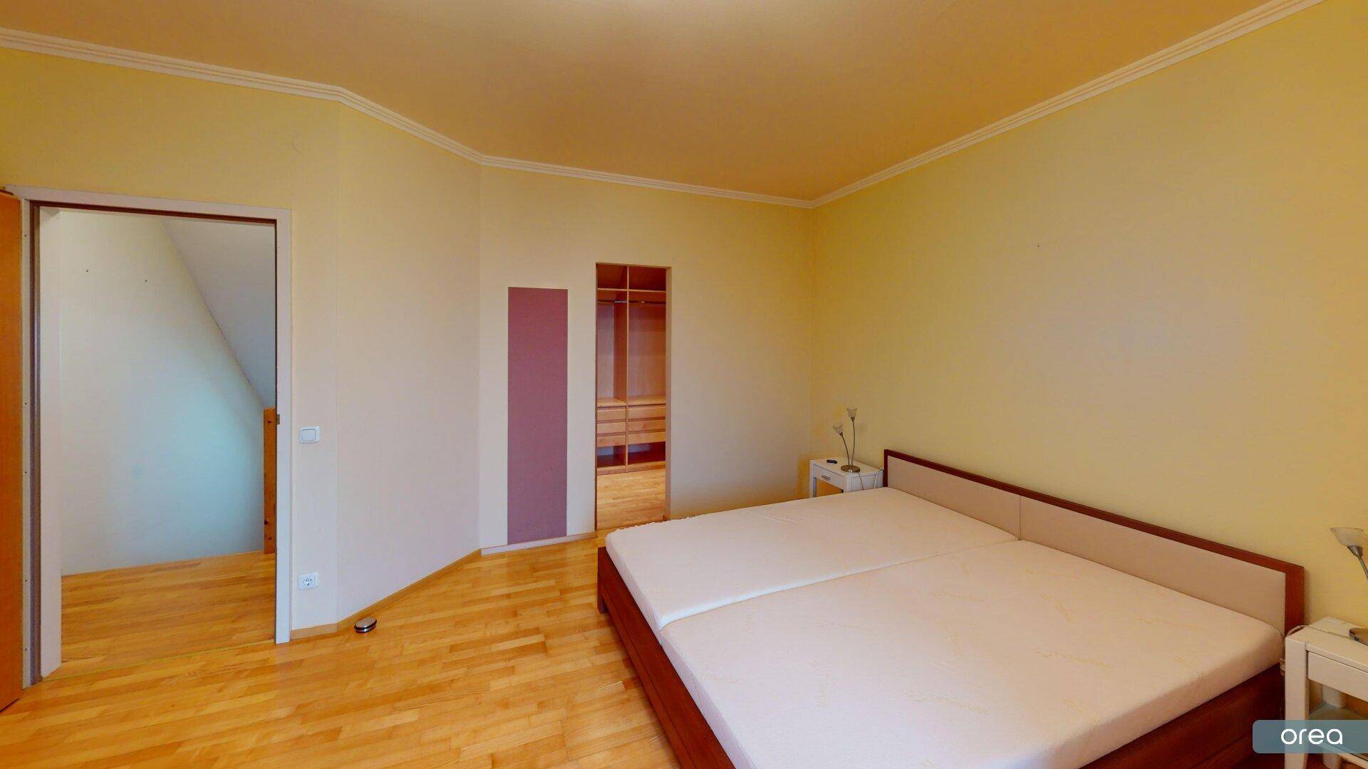 Schlafzimmer mit Doppelbett und Zugang zu einem begehbaren Kleiderschrank.