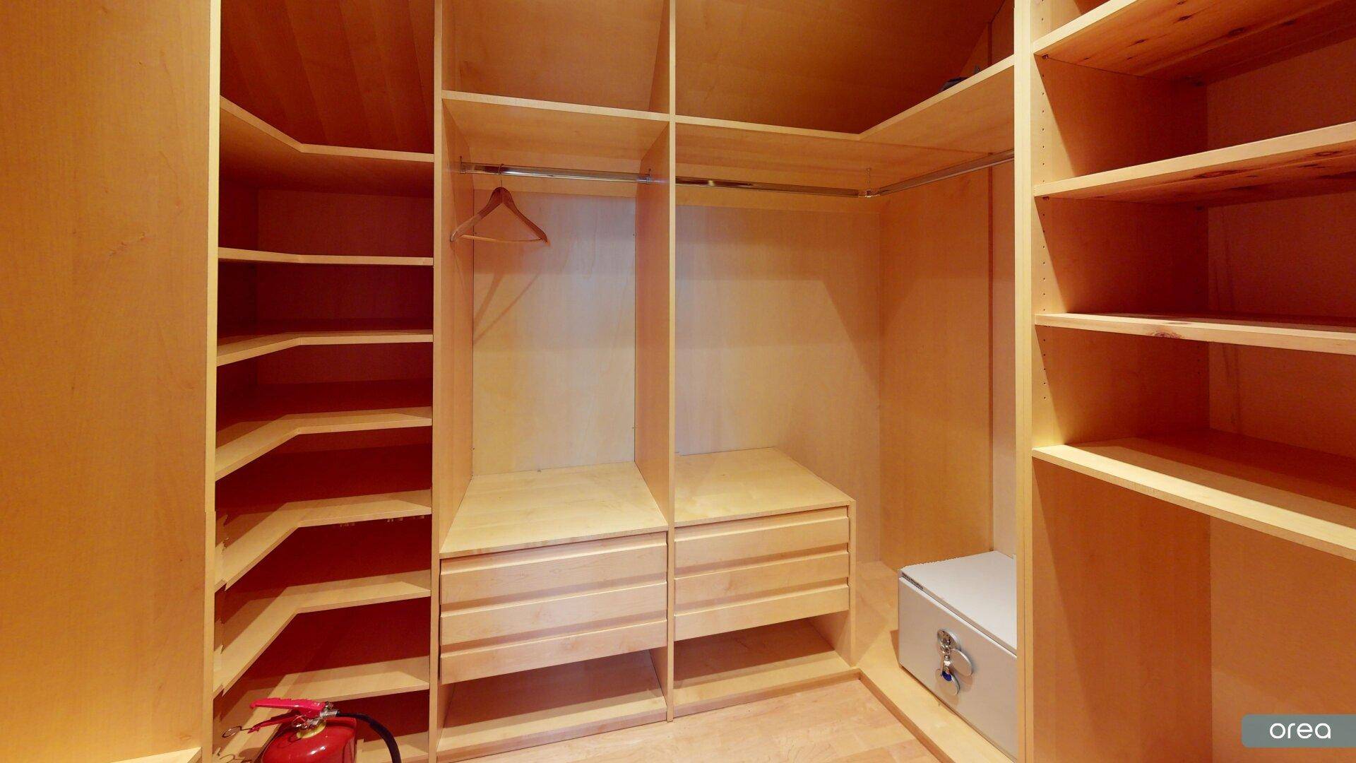 Begehbarer Kleiderschrank mit maßgefertigten Holzregalen und Kleiderstangen.
