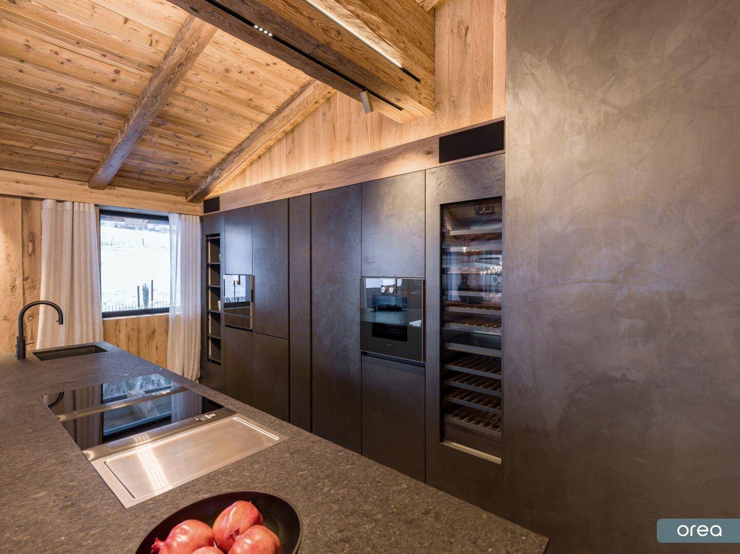Hochwertige Einbauküche mit dunklen Arbeitsplatten, Induktionskochfeld und integriertem Weinkühlschrank.