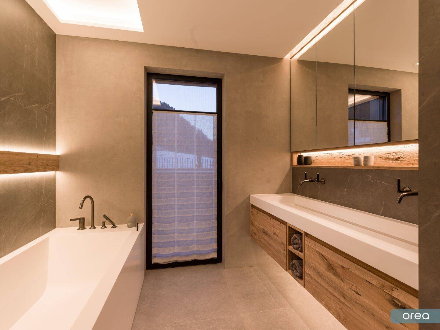 Modernes Badezimmer mit Badewanne, Doppelwaschbecken und indirekter Beleuchtung.