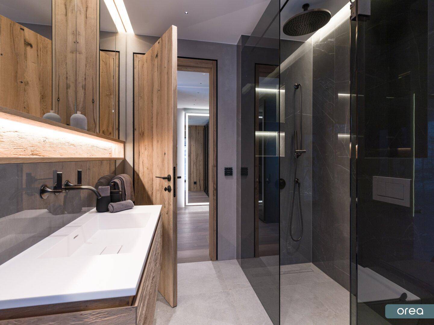 Modernes Badezimmer mit begehbarer Dusche, Doppelwaschbecken und Holzdetails.