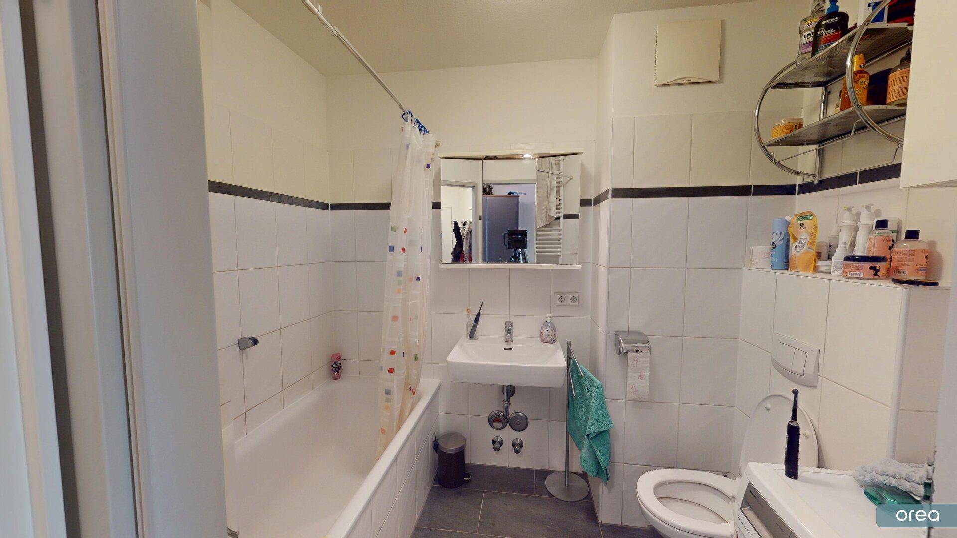 Helles Badezimmer mit Badewanne, WC und Waschbecken, ausgestattet mit weißen Fliesen.