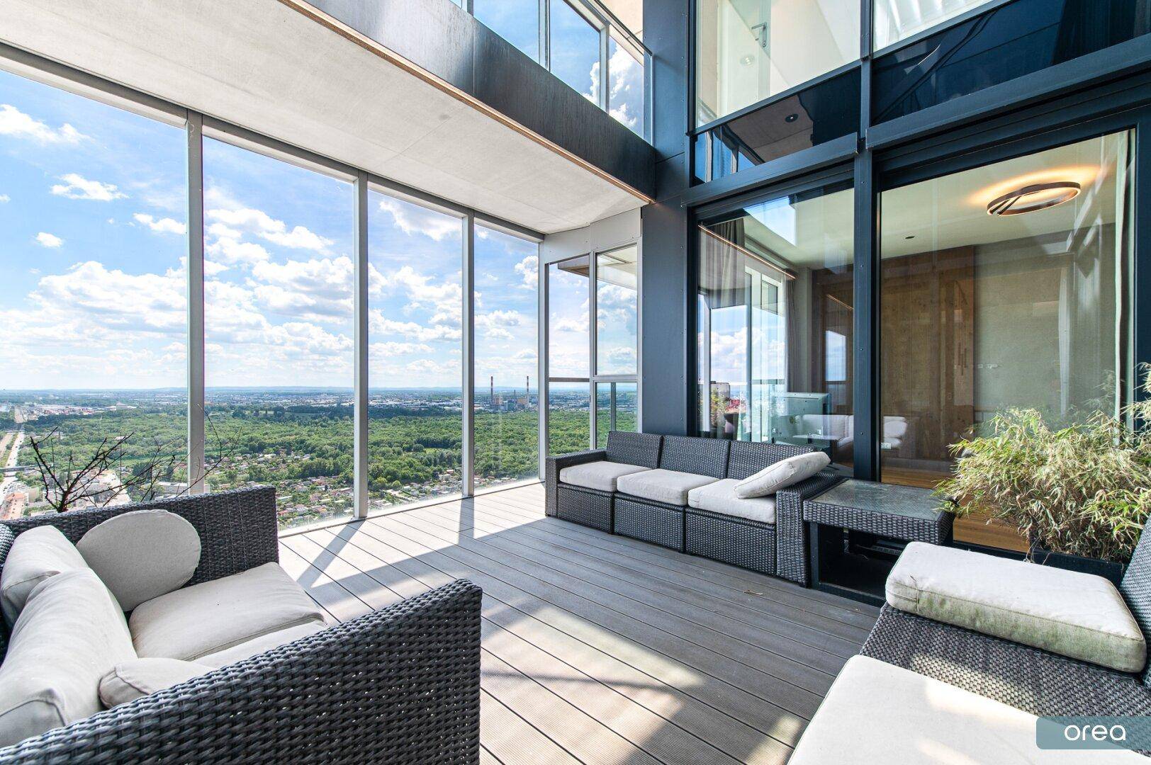 Große Terrasse mit bequemen Sitzgelegenheiten und atemberaubendem Blick über die Stadt und die Natur.