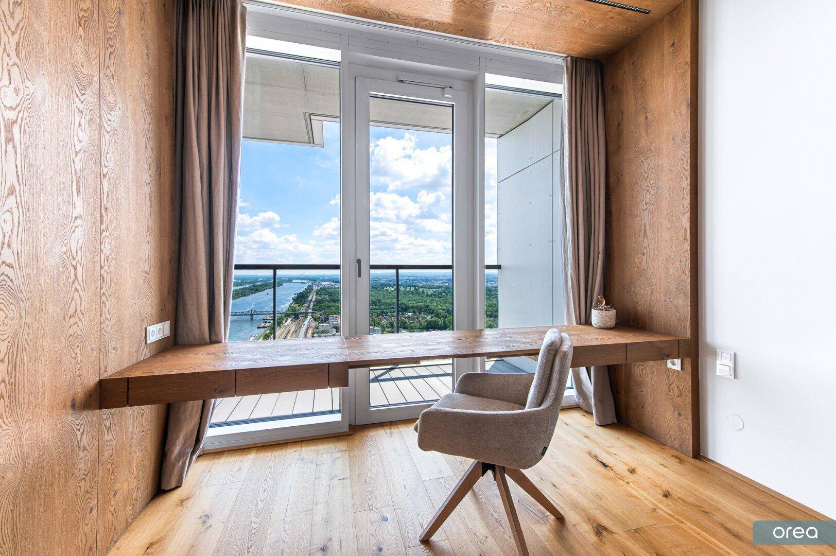 Helles Arbeitszimmer mit integriertem Schreibtisch, Holzverkleidung und weitem Blick.