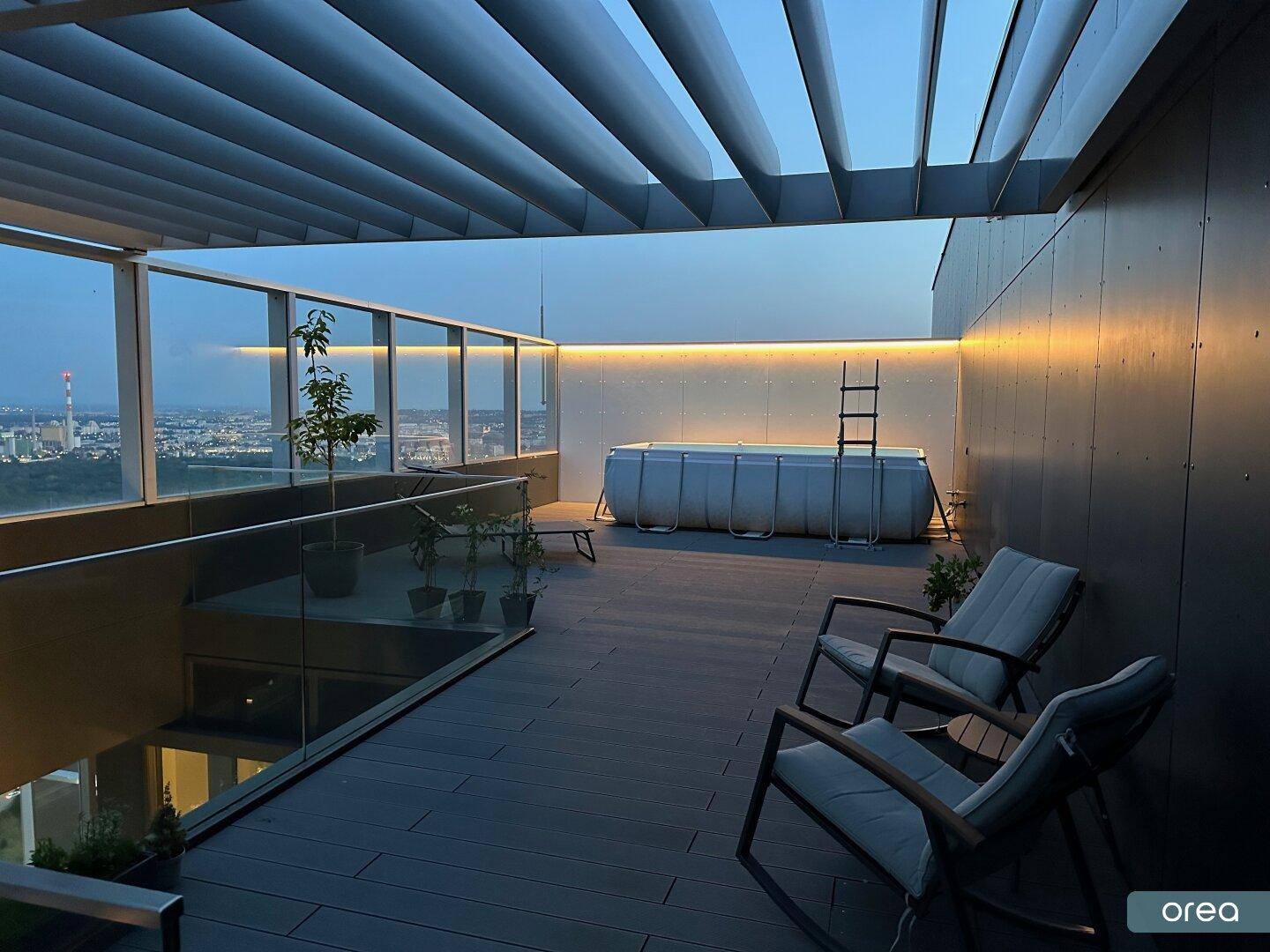 Dachterrasse am Abend mit kleinem Pool, Pergola und Stadtblick bei Dämmerung.