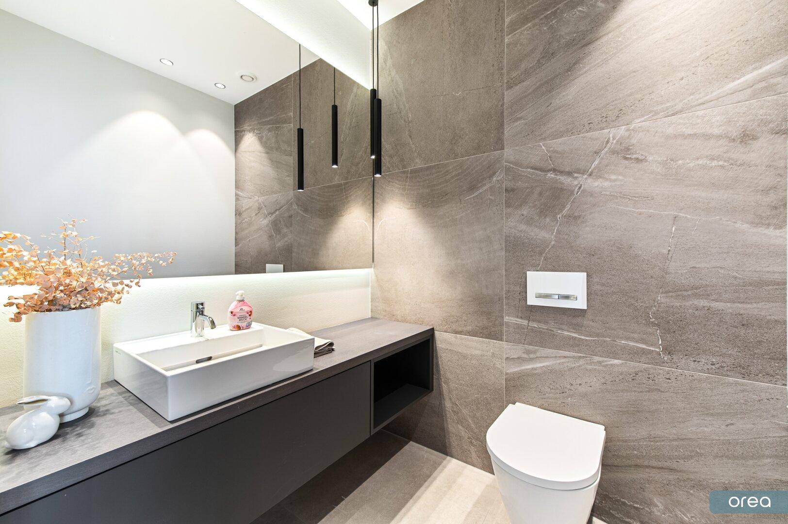 Modernes Gäste-WC mit eleganten Marmorfliesen, Wand-WC und stilvollem Waschbecken.