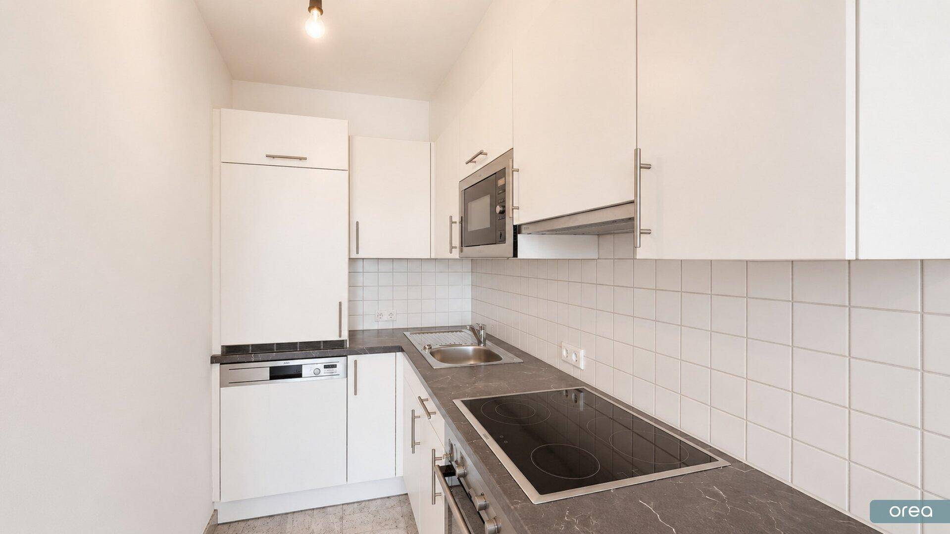 Moderne Einbauküche mit weißen Schränken, Induktionskochfeld und integrierten Geräten.