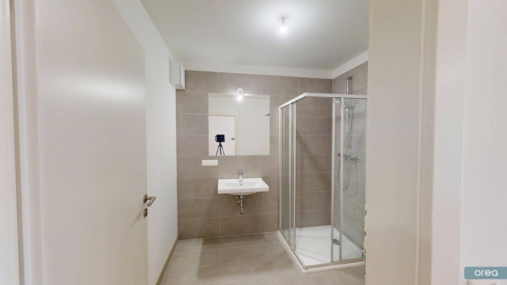 Modernes Badezimmer mit grauen Fliesen, Duschkabine und Einzelwaschbecken.
