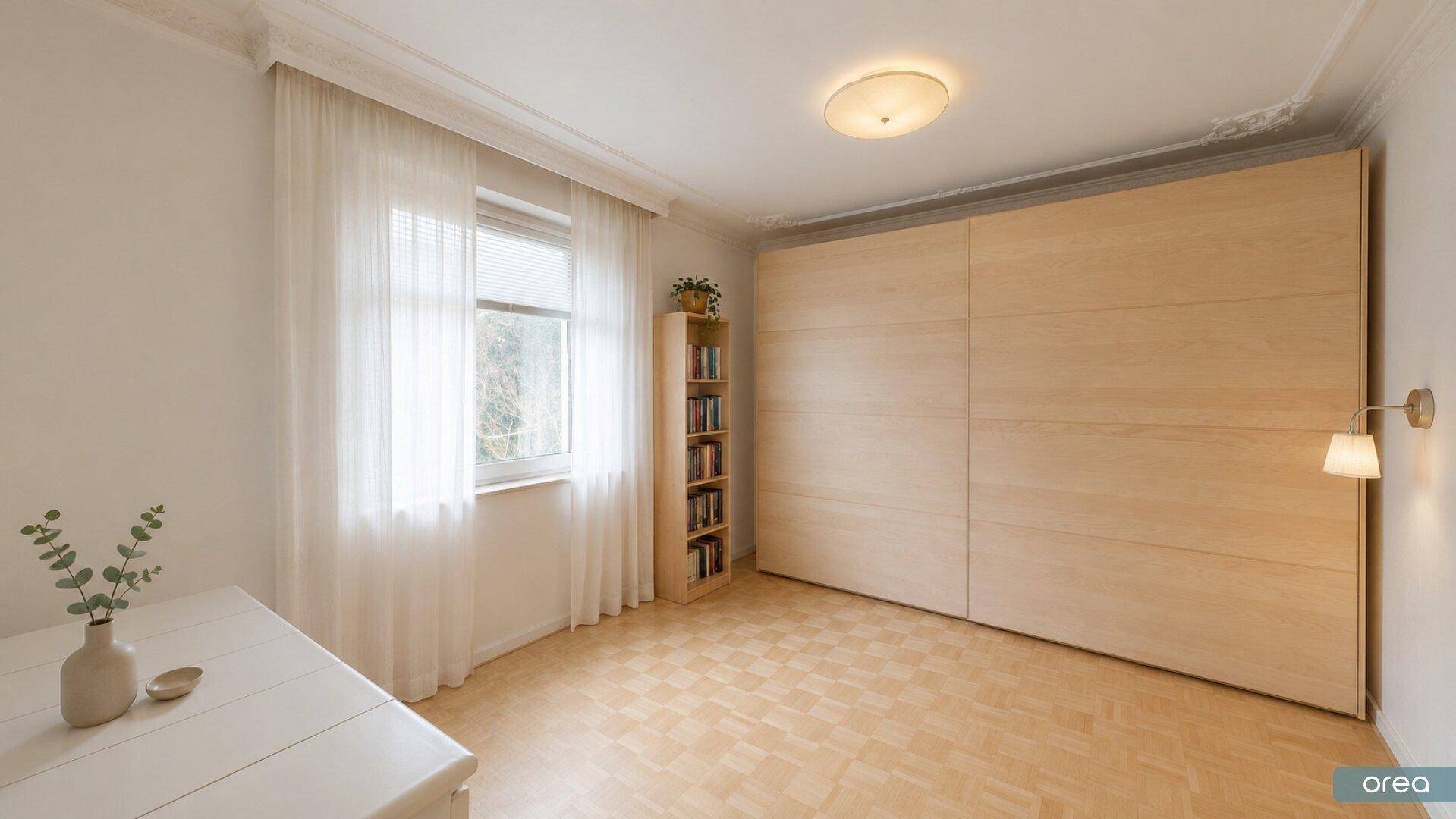 Helles Zimmer mit großem Einbauschrank, Parkettboden und Fenster mit Vorhängen.