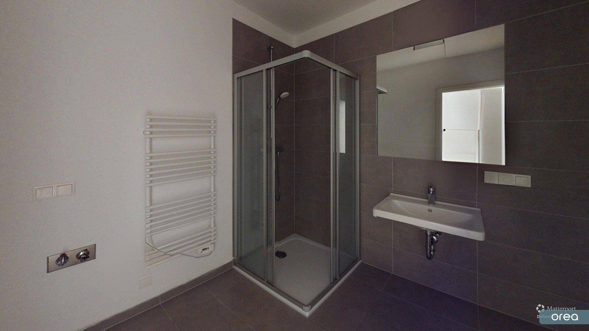 Modernes Badezimmer mit Eckdusche, Waschbecken, Spiegelschrank und beheiztem Handtuchhalter.