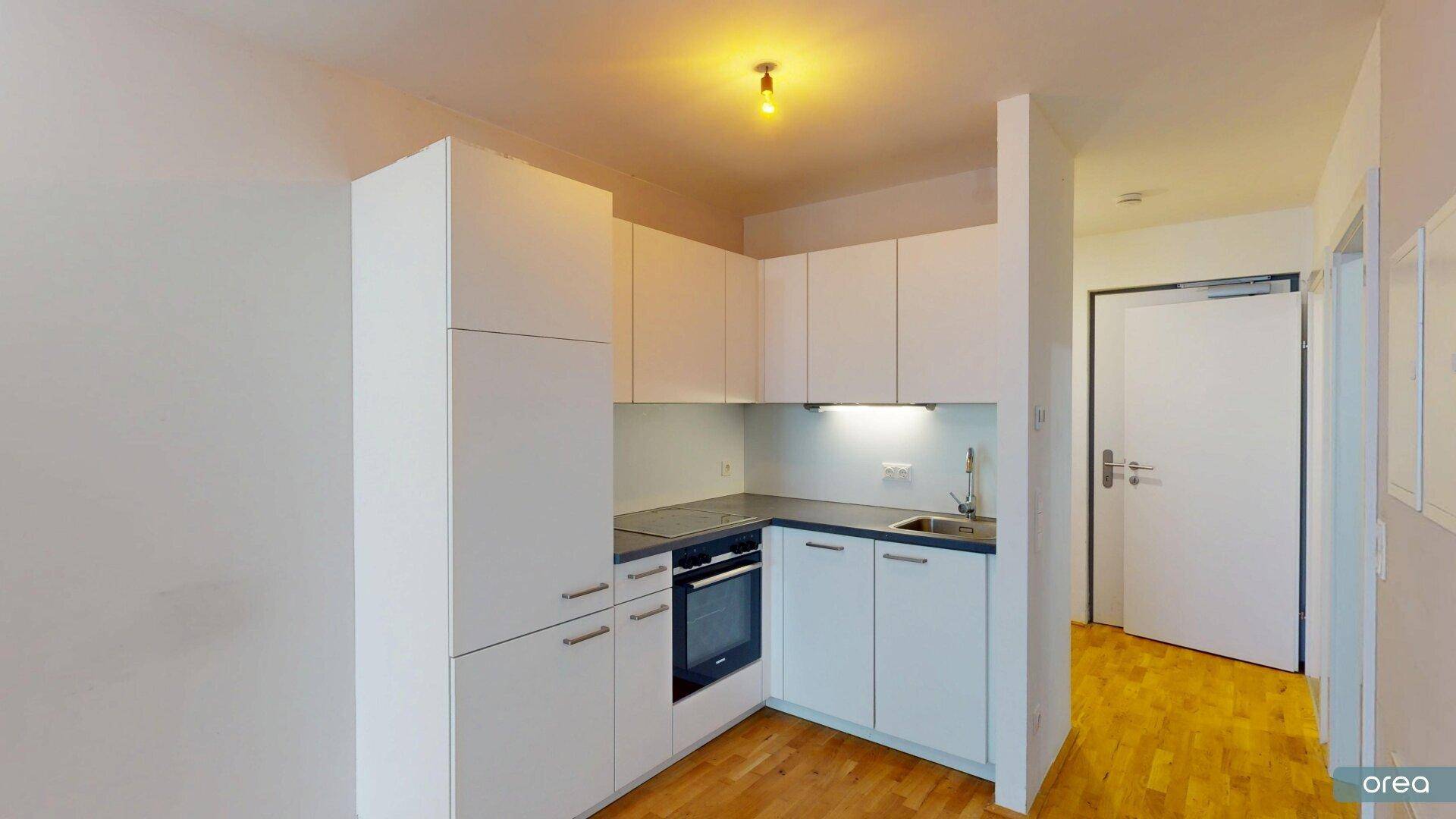 Moderne, kompakte Küchenzeile in Weiß mit integriertem Backofen und Kochfeld.